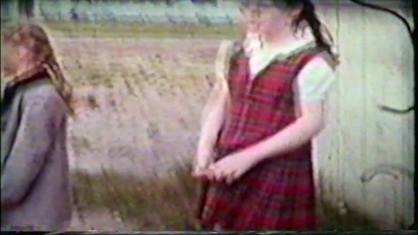 Vintage 8mm footage captures sweet moments of young sisters posing and waving for the camera outdoors