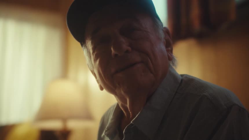 A close-up of a thoughtful U.S. Air Force veteran looking up with a heartwarming smile and laugh in his home