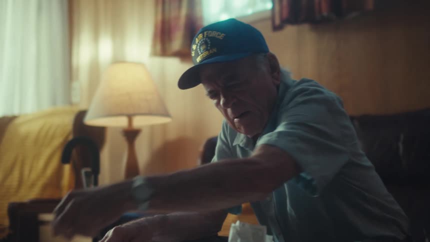 Worried elderly Air Force veteran sorts through a pile of bills and receipts while sitting on his couch