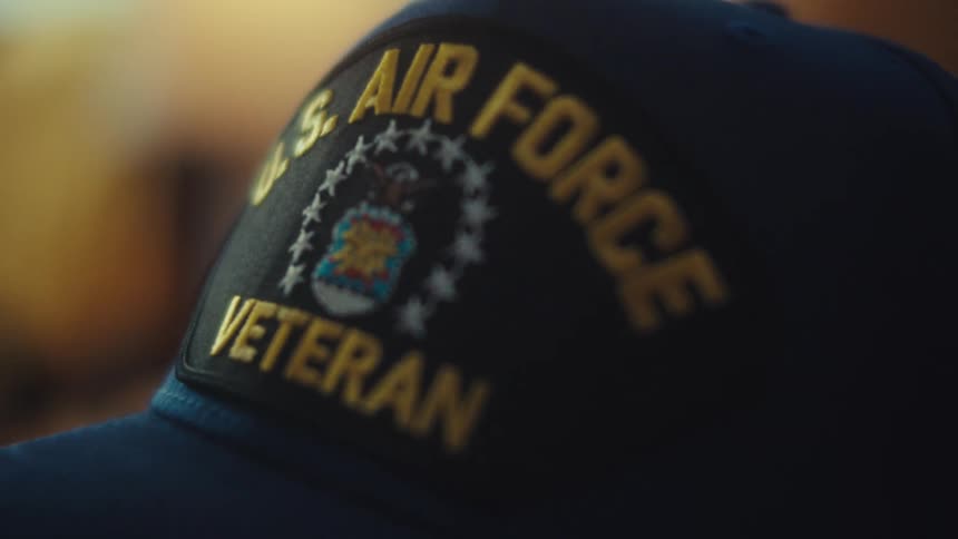 A close-up shot of a blue hat with an embroidered U.S. Air Force Veteran patch under warm lighting