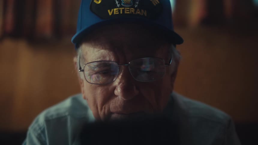 Close up of a pensive U.S. Air Force veteran scrolling on his smartphone, with the focus shifting from his face to the device