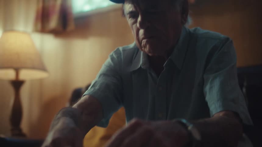 A worried elderly Air Force veteran sits at his table sorting through a large pile of bills and receipts