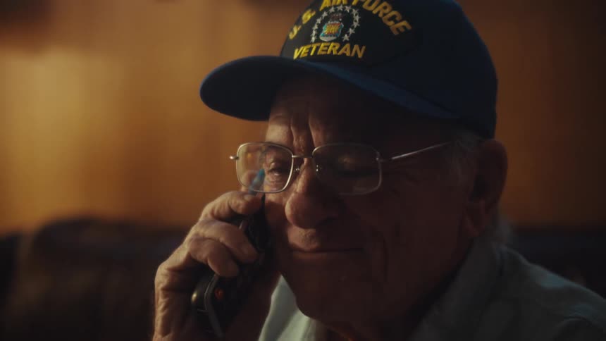 An elderly U.S. Air Force veteran has an emotional conversation on a landline phone