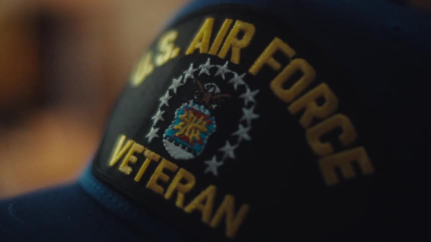 A close-up, rack focus shot reveals a U.S. Air Force Veteran patch on a hat