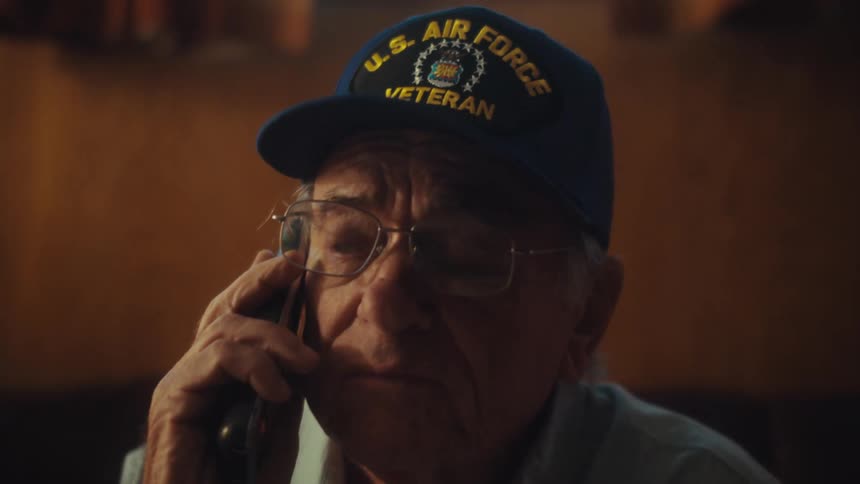 A pensive elderly U.S. Air Force veteran has a serious conversation on the phone in his home