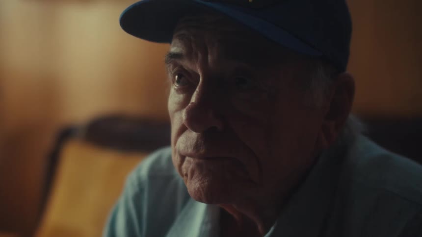A concerned elderly US Air Force veteran removes his glasses while looking over his bills, overwhelmed by financial stress