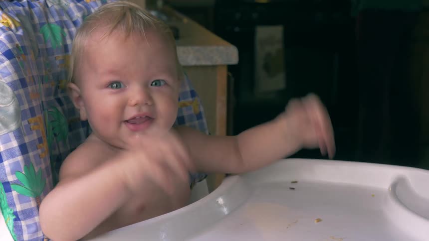 A baby pumps his arms in a high chair