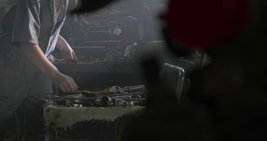 A person grabs tools from a cart