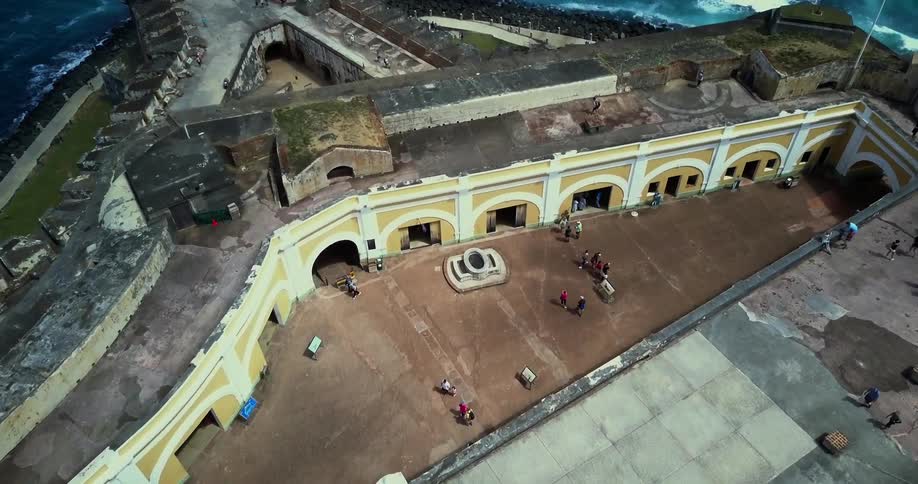 Aerial view of an old structure near the ocean and people walking in it
