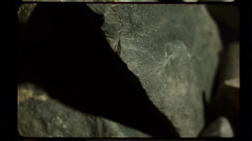 Gritty, vintage film stop-motion effect of abstract grey rocks in dramatic light