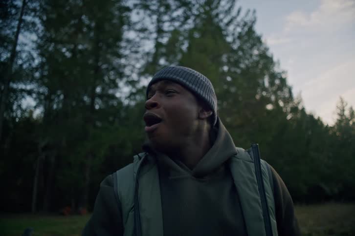 Two friends play a casual game of golf in a field at dusk, and one man reacts with a happy, surprised smile