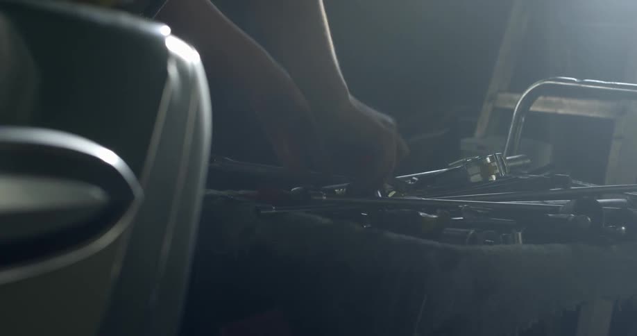 A person picks up tools to fix a car