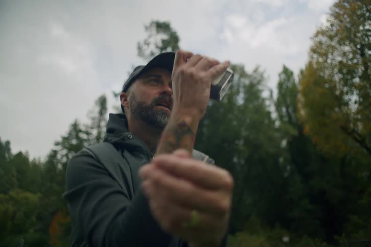 A male golfer pulls a rangefinder out of his bag and measures the distance on a beautiful course