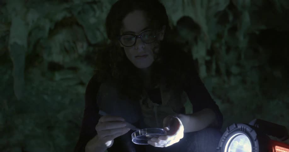 A woman is collecting samples from a cave floor
