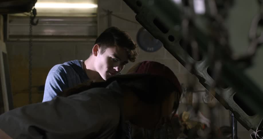 A man and woman work on a car together