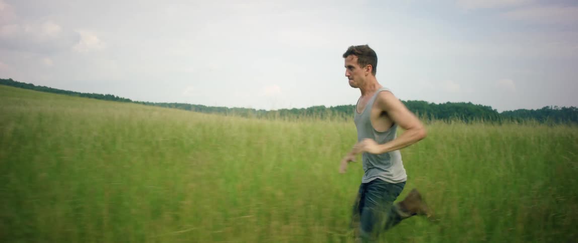 A man runs through a grassy field