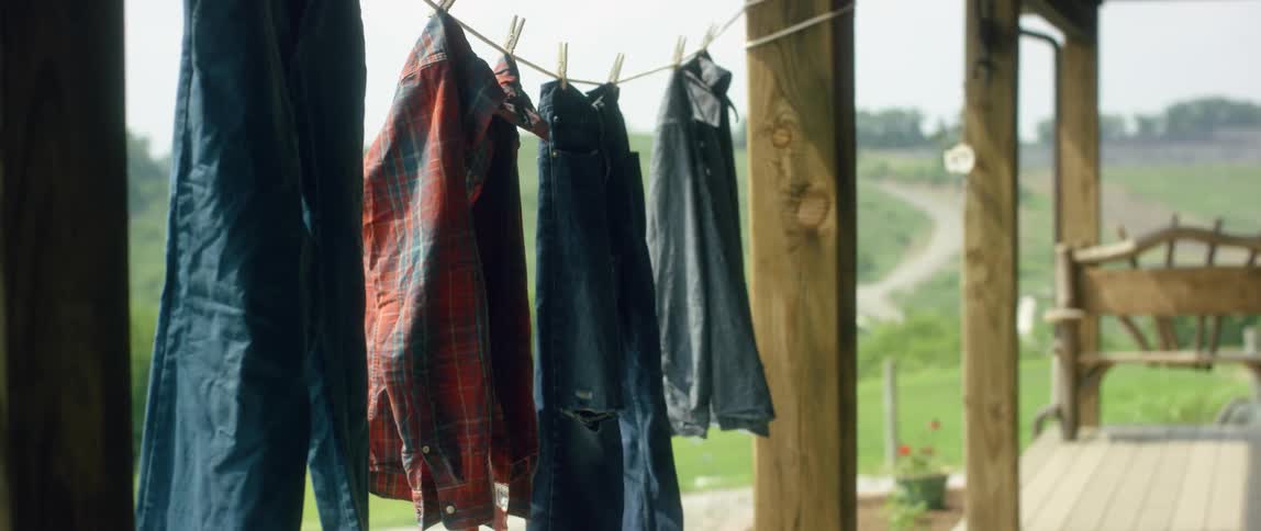 Shirts and jeans dry on a line hung between porch columns