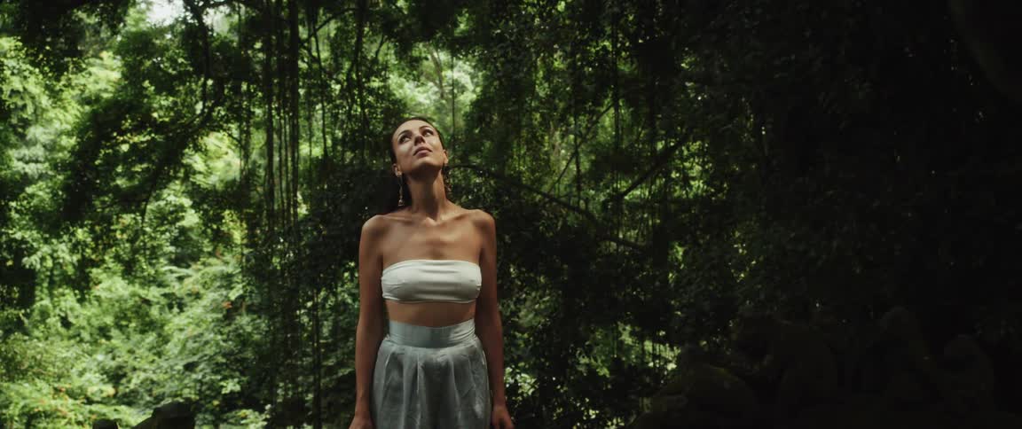 A slow reveal shows a woman looking up in awe, surrounded by the lush green canopy of a mystical jungle