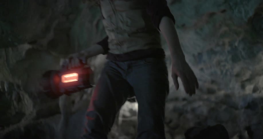 A woman uses a flashlight to look at cavern walls