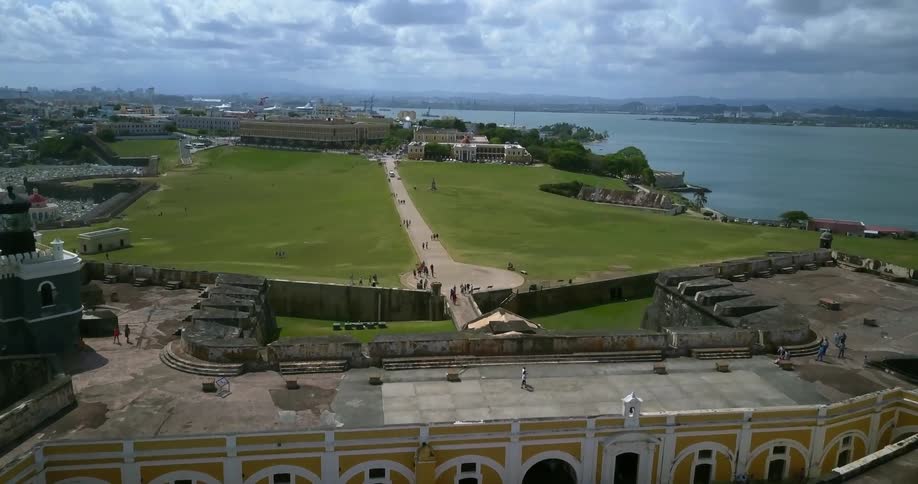 Tourists mill about an old fort in a coastal area