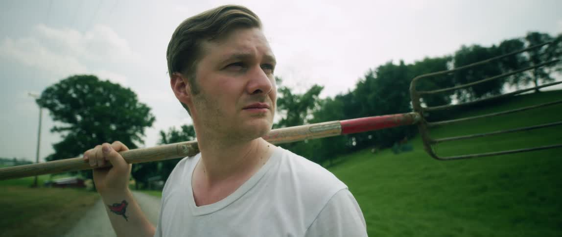 A man is holding a pitchfork on his shoulders