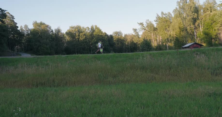 A man runs on a rural path surrounded by a lush green field and a forest on a sunny day