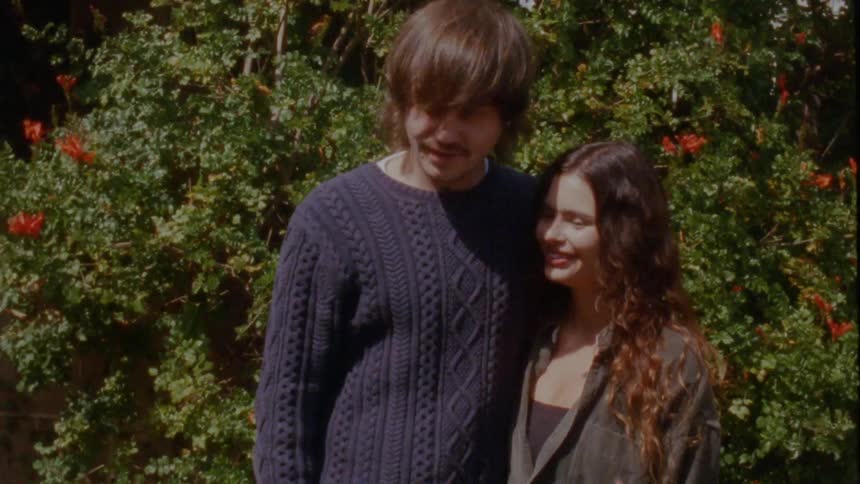 Vintage-style footage of an affectionate young couple smiling and embracing in a sunlit garden