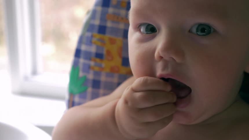 A baby is eating in the dining room