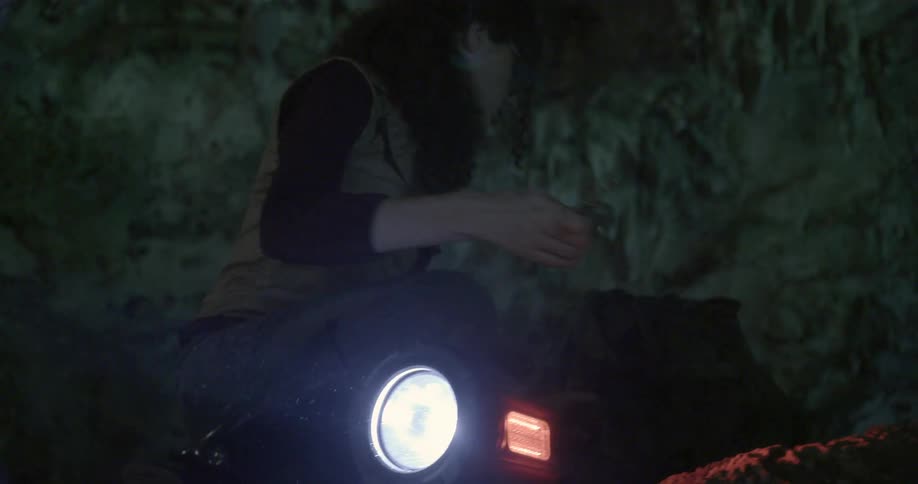 A woman is searching inside of a dark cave
