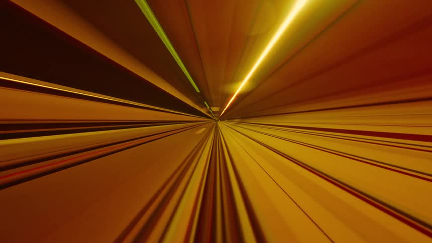 Abstract point-of-view time-lapse of a speeding subway train creating colorful light trails in a dark tunnel