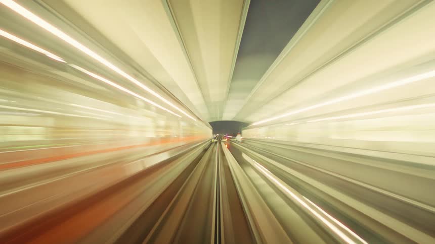 A high-speed point-of-view time-lapse from a monorail train as it races through a futuristic city at night, creating mesmerizing light trails