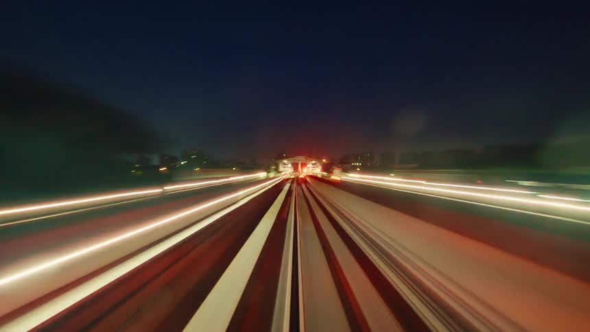Futuristic POV time-lapse of a high-speed train journey at night, where urban lights blend into a symphony of colorful streaks