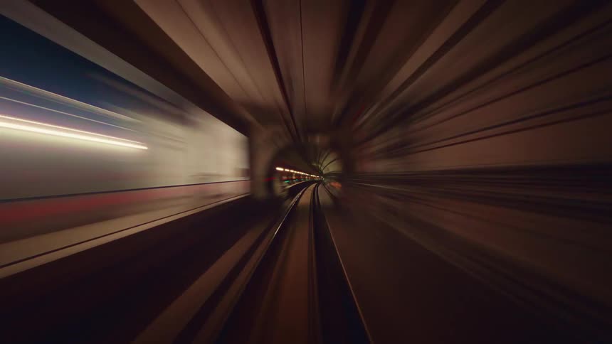 A trippy and futuristic point-of-view time-lapse of a train speeding through an underground tunnel, creating vibrant streaks of colorful light