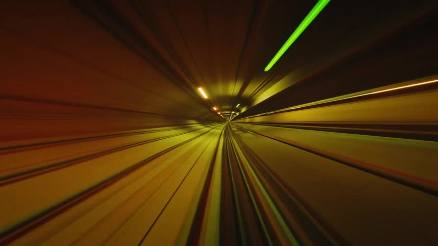 A surreal point-of-view time-lapse of a train speeding through a tunnel, with colorful light trails creating a psychedelic effect