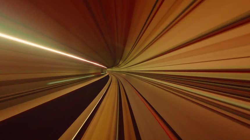 Abstract, colorful time-lapse of a fast-moving subway train traveling through an underground tunnel