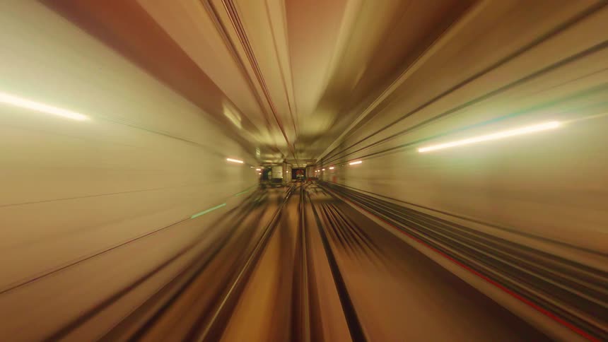 Abstract, colorful time-lapse of a fast-moving subway train traveling through an underground tunnel
