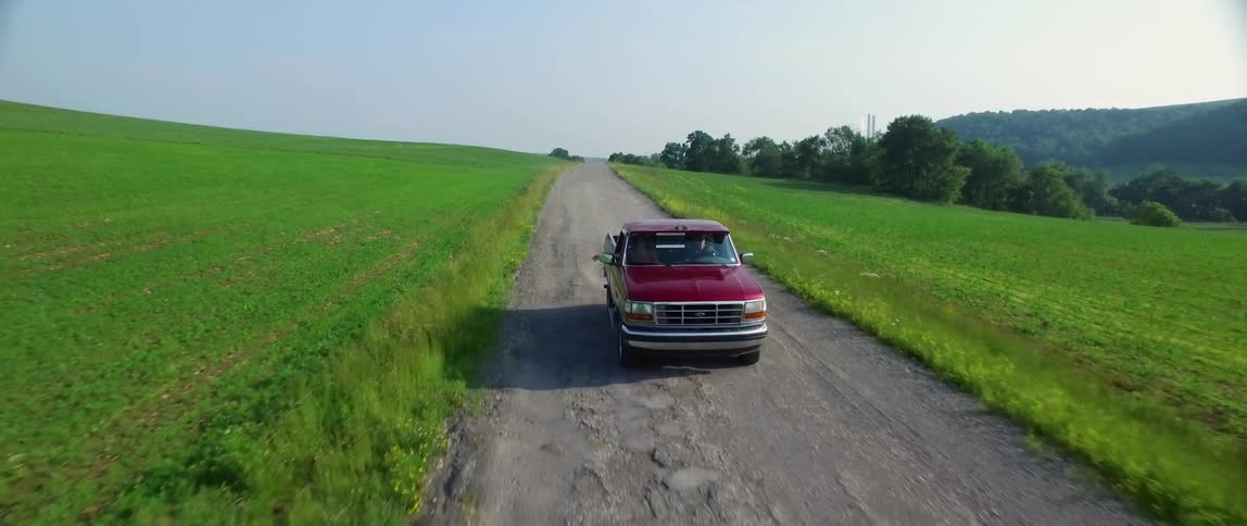 An old pickup truck is being driven along a rural road