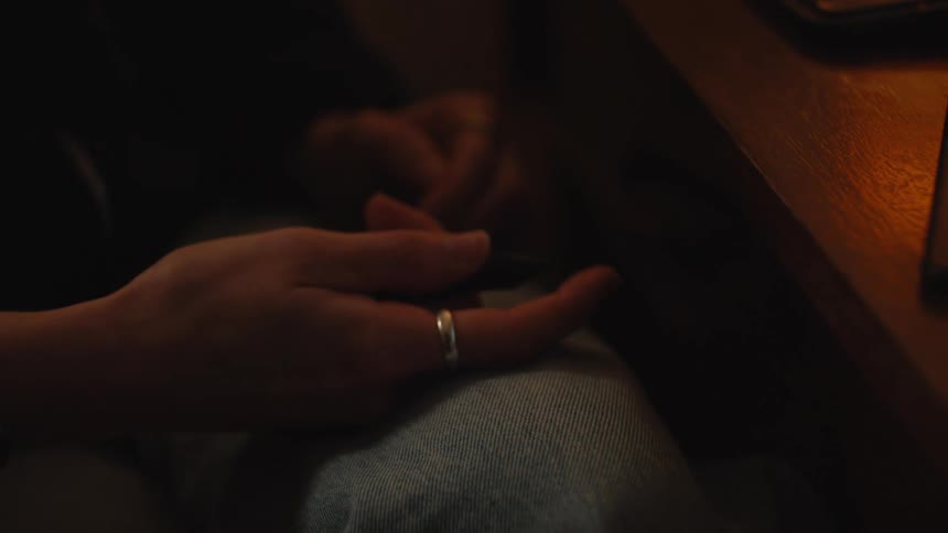 A designer's hands nervously fiddle with a stylus before they begin sketching on a graphics tablet in a dimly lit, creative workspace
