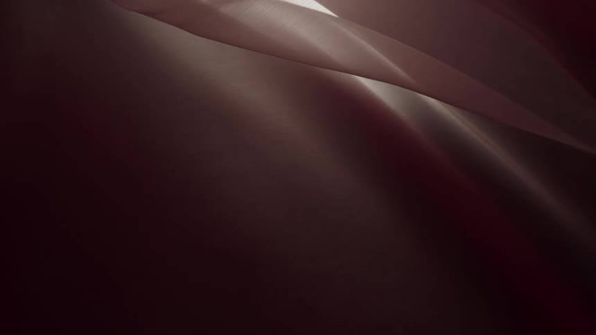 Elegant and smooth dark maroon fabric flows gracefully as an abstract background
