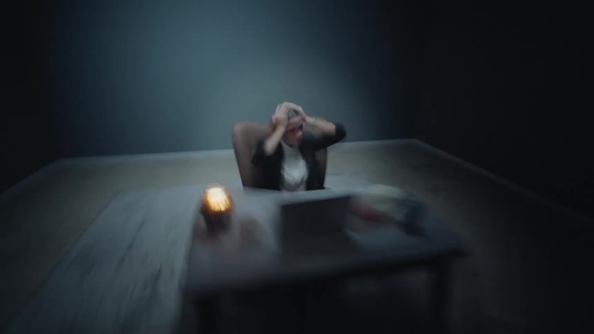Chaotic and disorienting clip of a woman in a suit having a mental breakdown or panic attack at her desk in a stark office