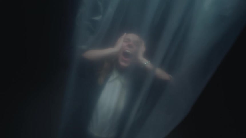 A terrified person screams in anguish while trapped behind a translucent plastic sheet in a dark room