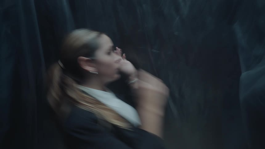 A disoriented and stressed woman in a business suit feels trapped and panicked inside a dark, blurry space