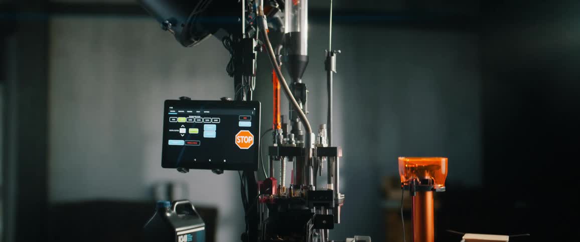 A sophisticated, automated ammunition reloading press operates in a workshop, controlled by a digital interface