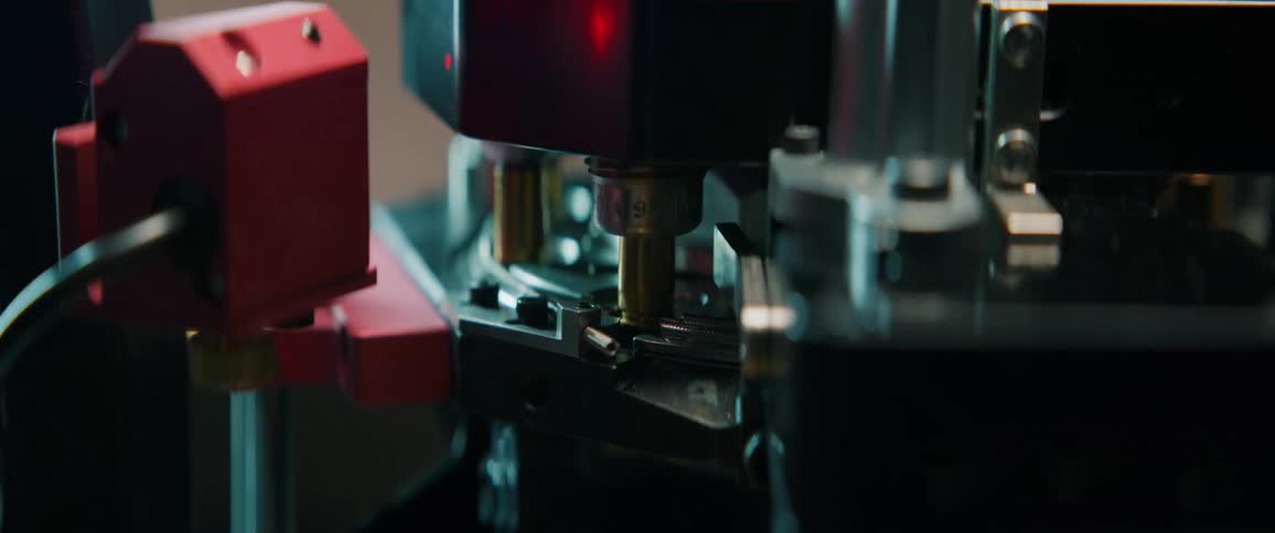 Slow motion close-up of a reloading press automatically manufacturing bullets in a workshop