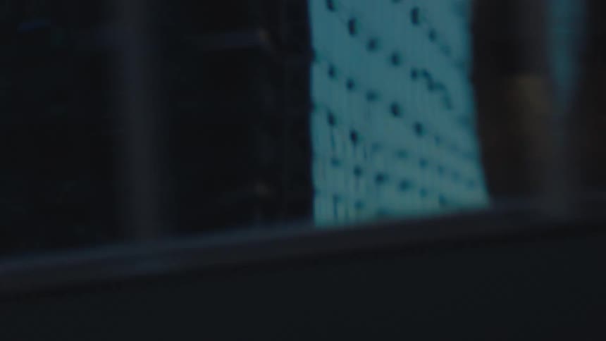 A side-scrolling view captures the distorted and abstract reflections of a city's architecture and traffic on glass skyscrapers