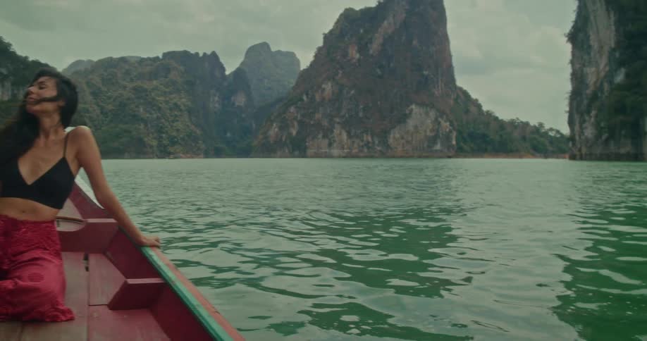 A beautiful woman enjoys a scenic long-tail boat ride through a tranquil lake surrounded by majestic limestone cliffs
