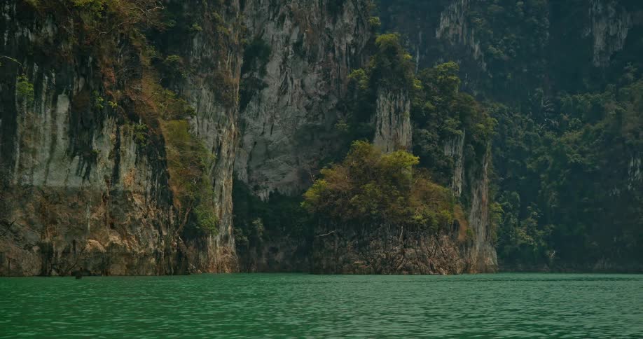 Majestic limestone cliffs rise from the tranquil, emerald green waters of a vast lake