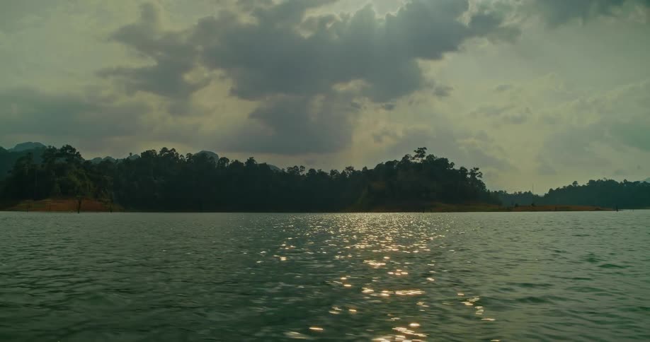 A serene boat ride on a vast lake surrounded by tropical jungle as the sun glitters on the water's surface
