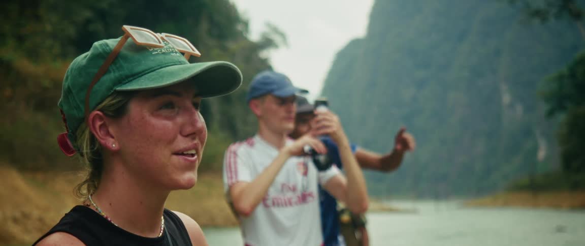 A group of friends enjoys the stunning scenery of a tropical mountain lake while one takes a picture on his phone