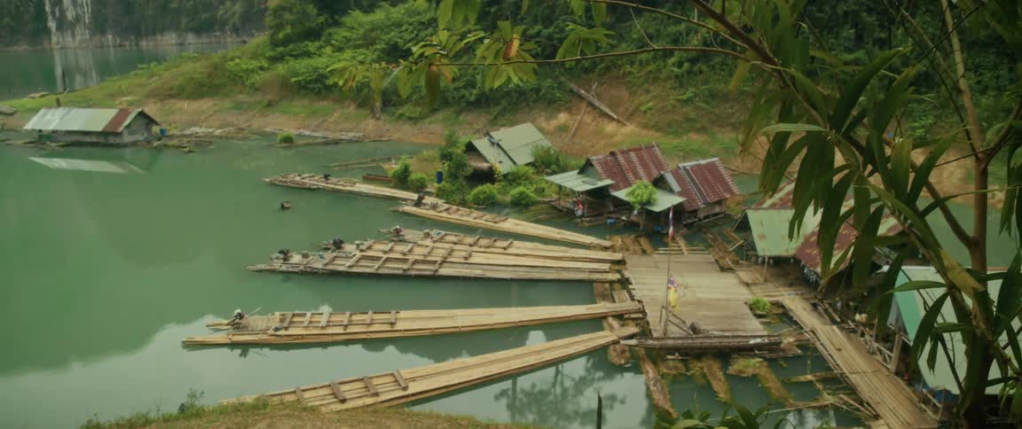 High angle view of a rustic floating village with bamboo rafts docked on a tranquil jungle river